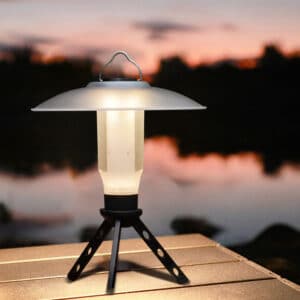 Lampe Camping d'Urgence Portable et Étanche sur une table en bois sur fond d'un coucher de soleil rose