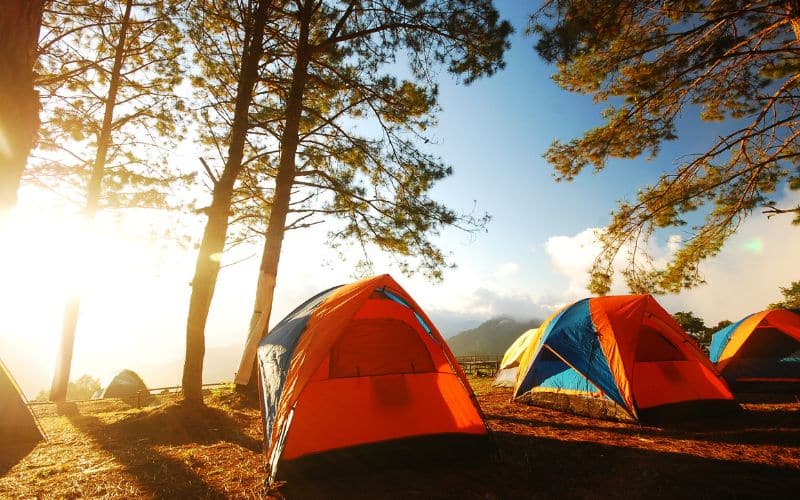 Deux tentes, oranges et bleues, installées en bord de forée, avec le soleil rasant.